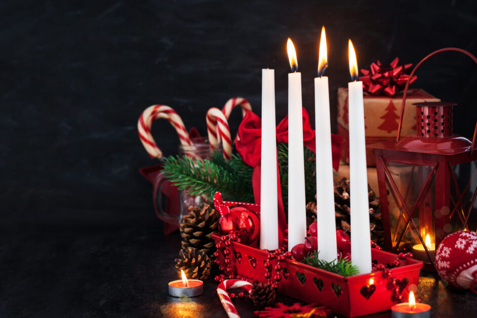 Four Christmas Advent candles and holiday decorations around on