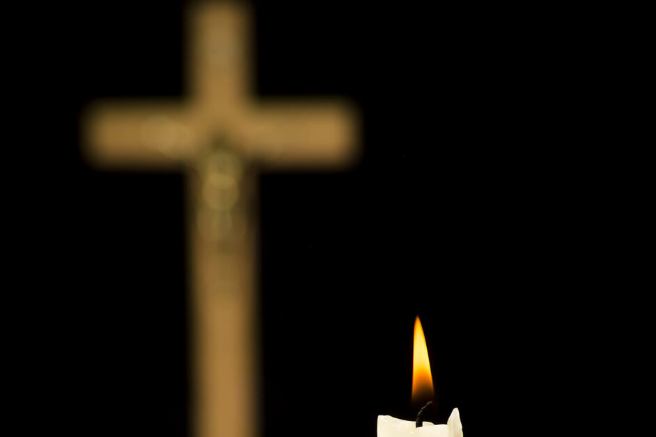 Christian religion concept, lit candle on a crucifix background