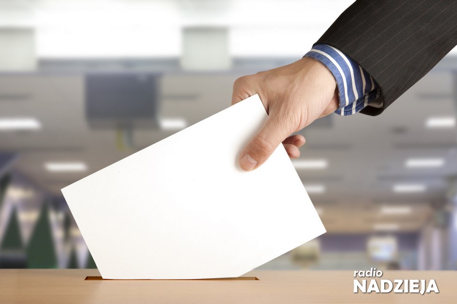 Hand putting a voting ballot in a slot of box